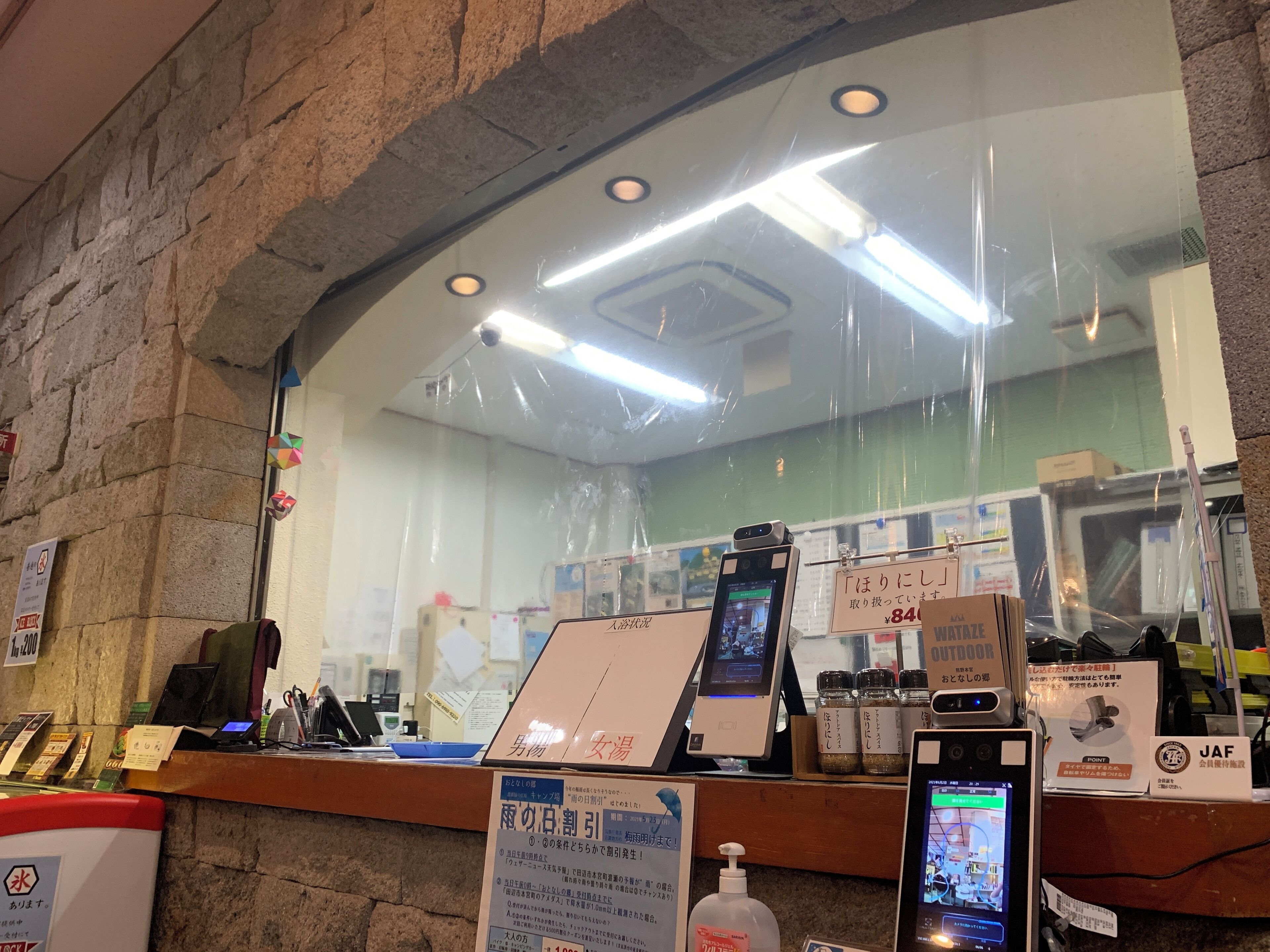 A reception area with a stone wall, a reception desk, a computer, and a sign indicating a 24-hour service.