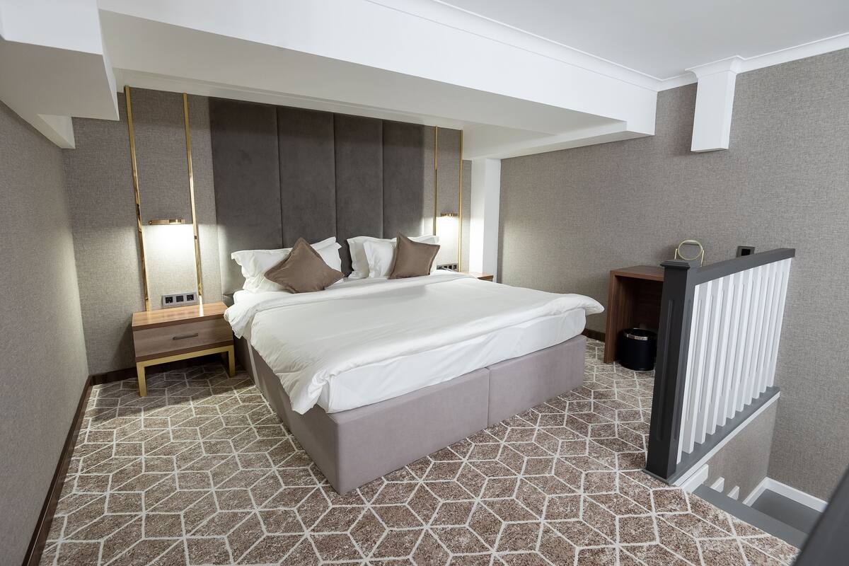 Una habitación de hotel moderna con una cama grande, mesitas de noche y un banco empotrado.