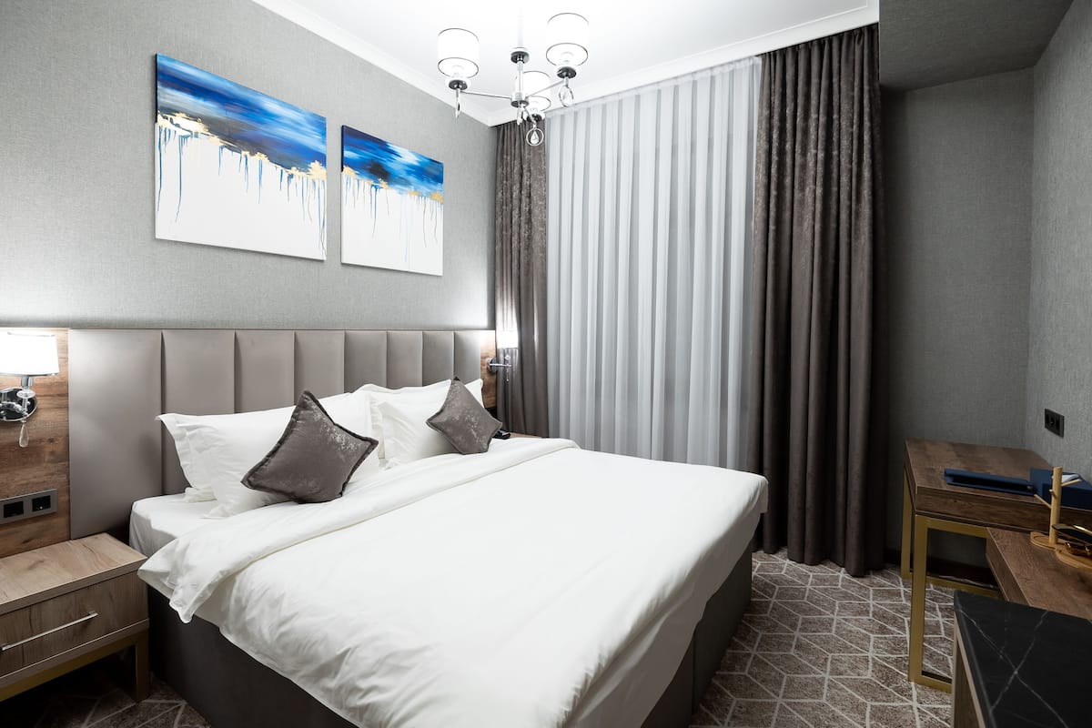 Una habitación de hotel moderna con una cama grande, una mesita de noche, un escritorio y una silla.