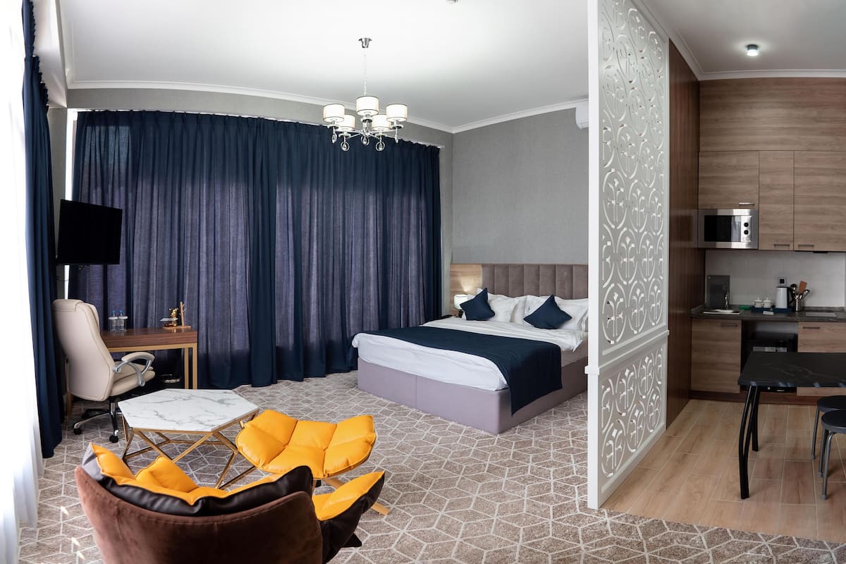 Una habitación de hotel con cama, escritorio, silla, sofá y kitchenette.