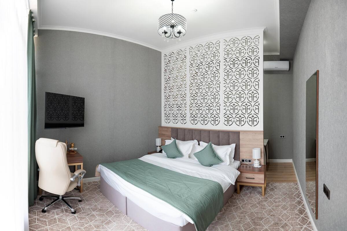 Una habitación de hotel moderna con una cama grande, un escritorio y una silla.