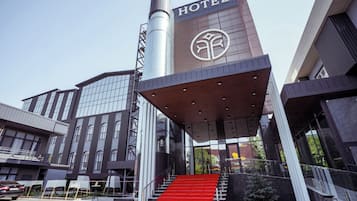 A modern hotel with a prominent "HOTEL" sign, a red carpeted staircase, and a large glass facade.
