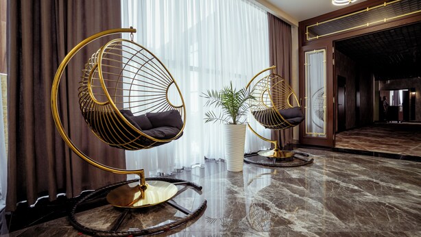Una habitación moderna con dos sillas colgantes, piso de mármol y un ventanal con cortinas.