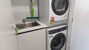 Un espace buanderie compact comprenant un lave-linge, un sèche-linge et un évier.