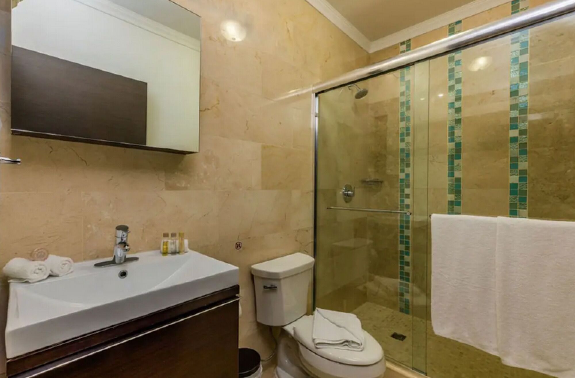 A bathroom with a glass-enclosed shower, a sink with a mirror, and a toilet.
