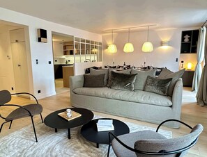 A modern living room with a sofa, two black coffee tables, and a patterned rug. - Elegant family flat with lift - Luxembourg Gardens (Paris)