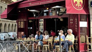 A cafe with outdoor seating, a red awning, and a sign reading "Brasserie parisienne 1791".