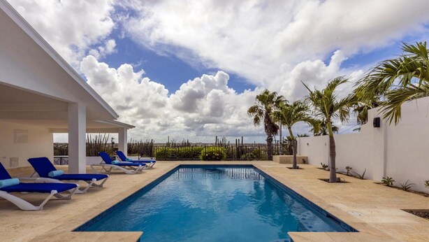 A swimming pool with blue lounge chairs, a covered seating area, and palm trees. - Breathtaking Views 2br3ba Private Pool Large Space (Noord)