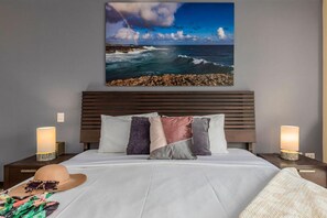 Relax in comfort with a large bed, two bedside tables, and a framed coastal view.