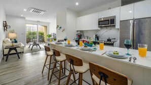 A modern kitchen with a central island, stainless steel appliances, and a dining area with bar stools. - NEW 2BR Condo in of Palm Beach Walk 2 Beach (Noord)