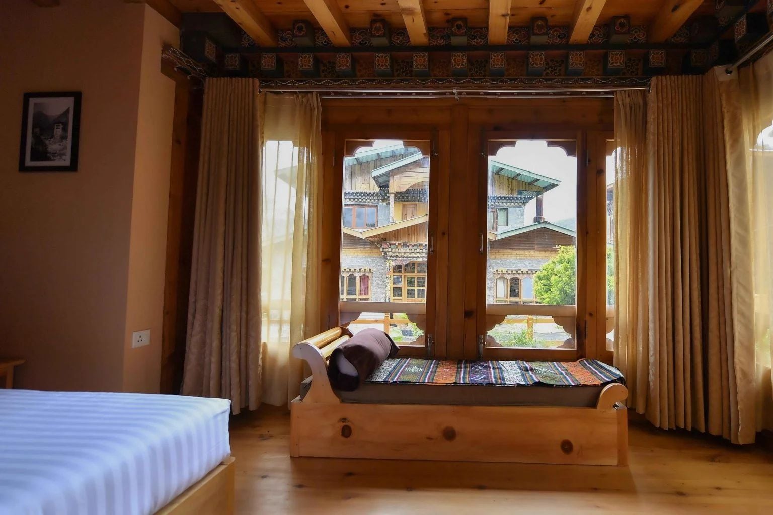 Un lit en bois donnant sur des bâtiments traditionnels.