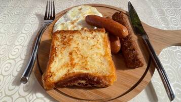 A breakfast plate with toast, sausages, and scrambled eggs on a wooden board.