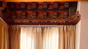 Una habitación con dos sillas y una mesita, techo decorativo y cortinas.