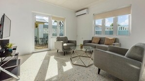 A modern living room with a sofa set, a coffee table, and a TV. - 3BR Home w Pool in Downtown 5min Walk 2 Beach (Oranjestad)