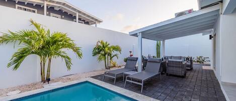 A pool area with lounge chairs and a covered patio.