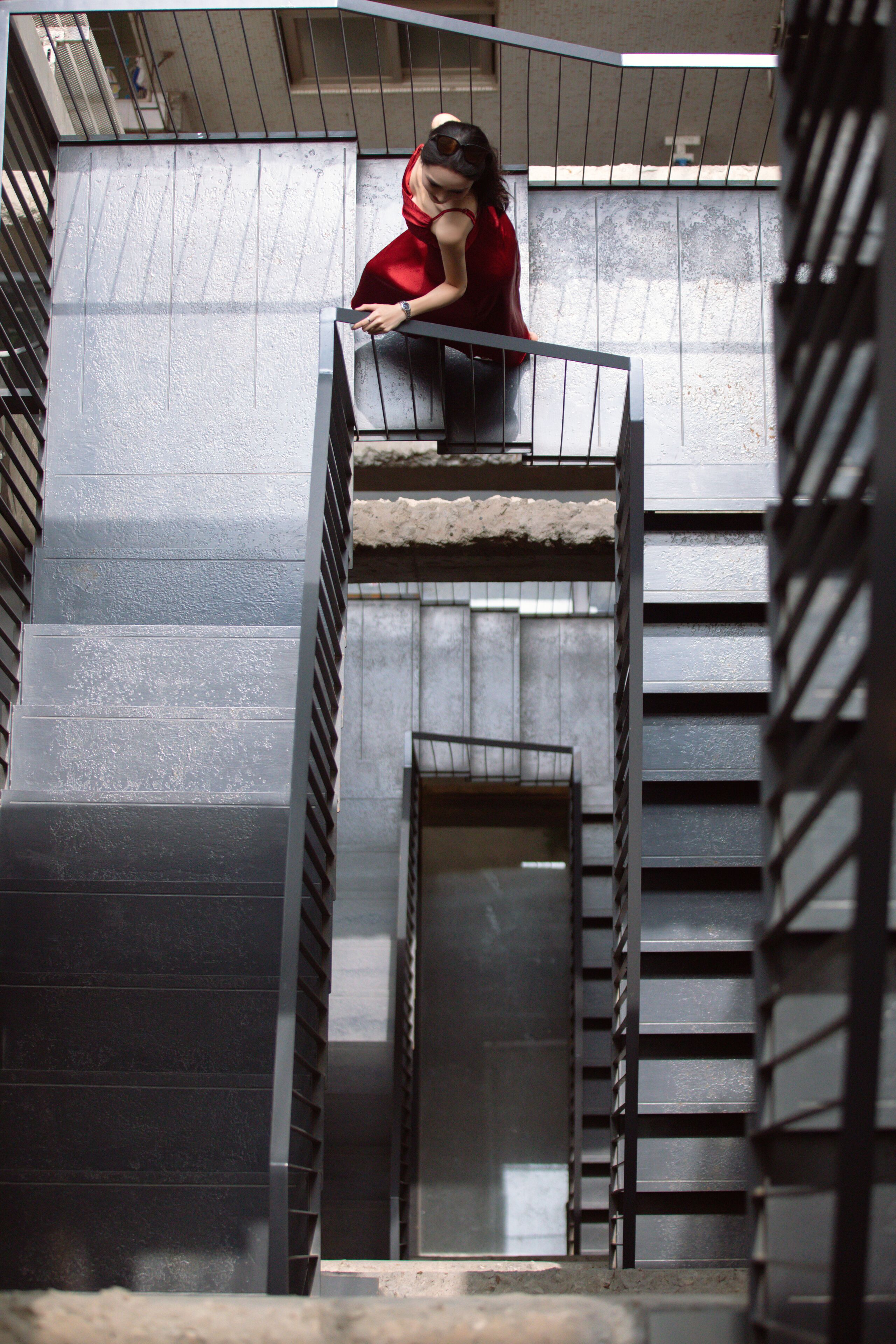A person on a narrow, metal staircase with a metal railing.