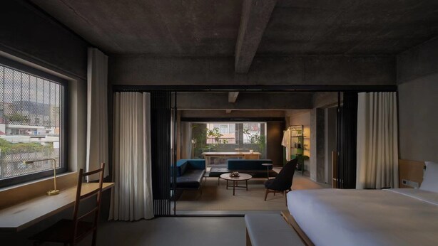Habitación de hotel moderna con una cama grande, un escritorio y una zona de estar con sofá y una mesita.