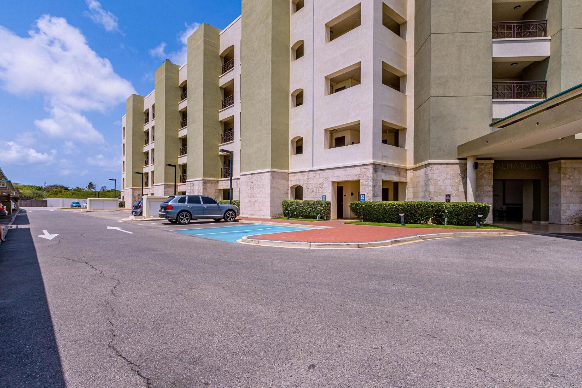 A multi-story hotel with a central courtyard, a parking area, and a building entrance.