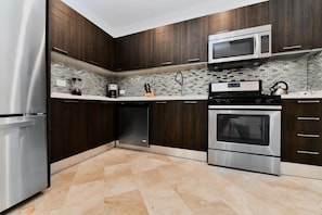 A modern kitchen with dark wood cabinets, stainless steel appliances, and a tiled backsplash. - Amazing 1BR 2BA Condo Great Location w Pool GYM (Noord)