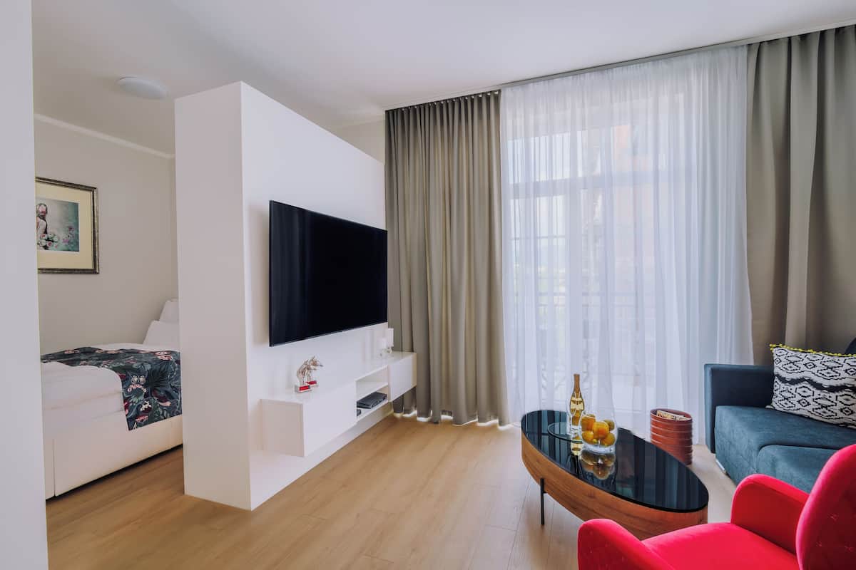 A modern living room with a flat-screen TV, a sofa, a coffee table, and a dining table.