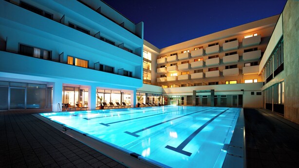 A swimming pool with clear lane markings, surrounded by a multi-story building with balconies and large windows. - Rezidencia OPERA (Turcianske Teplice)