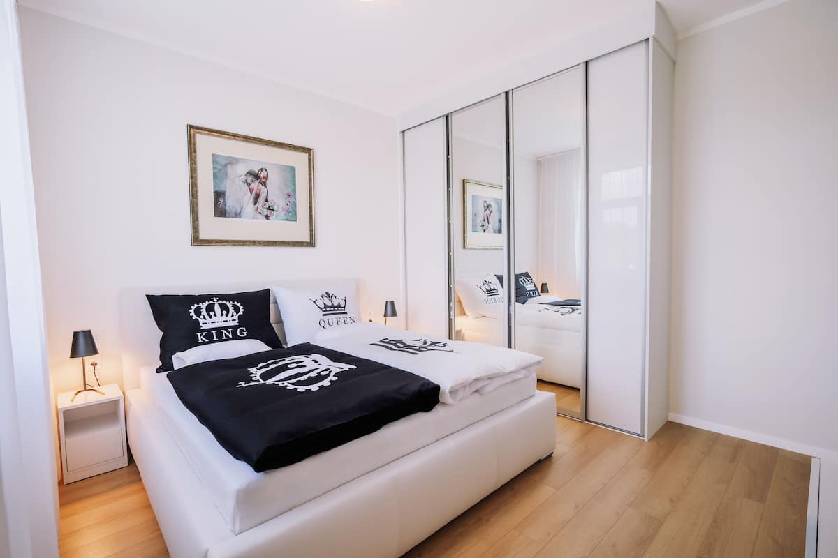 A bedroom with a bed, a nightstand, a mirror, and a wardrobe.