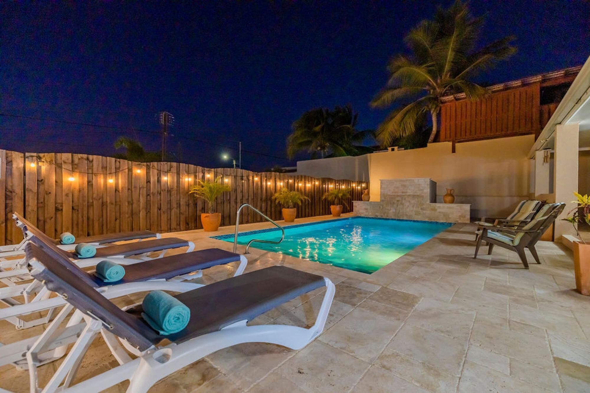 Un área de piscina al aire libre con sillones de descanso y una valla de madera.