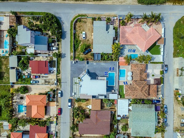 Vue aérienne d’un quartier résidentiel avec des maisons, une piscine et une route.