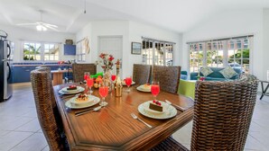 Un coin repas avec une table en bois dressée pour quatre personnes, entourée de chaises en osier.