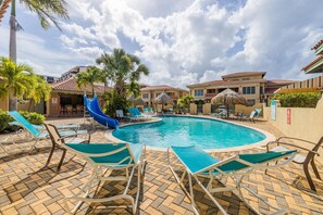 Una piscina con sillas de descanso, un tobogán y palmeras.