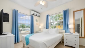 Une chambre d’hôtel équipée d’un lit, de tables de chevet, d’un téléviseur, d’un appareil de climatisation et d’une fenêtre avec des rideaux.
