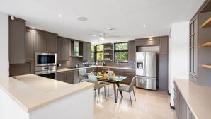 Uma cozinha moderna com armários escuros, eletrodomésticos de aço inoxidável e uma ilha central com cadeiras.