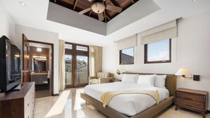Quarto de hotel moderno com uma cama grande, televisão, escrivaninha com cadeira e varanda com cortinas.