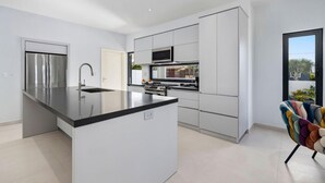 A modern kitchen with a central island, stainless steel appliances, and white cabinetry.