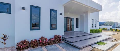 A modern house with a flat roof, large windows, and a covered porch.