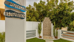 A welcome sign at a beach property with a stone wall and cacti. - Brand NEW 3BR 2BA Villa With Amazing Amenities (Noord)