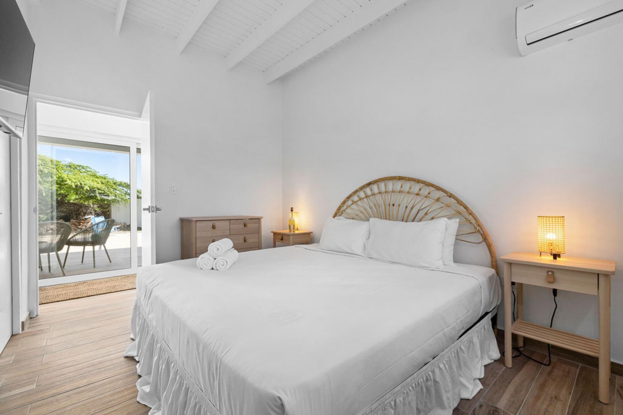 A bedroom with a bed, bedside tables, and a view of the outdoors.