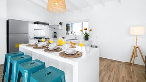 Une cuisine moderne dotée d’un îlot central, d’un réfrigérateur et d’un coin repas avec des tabourets.