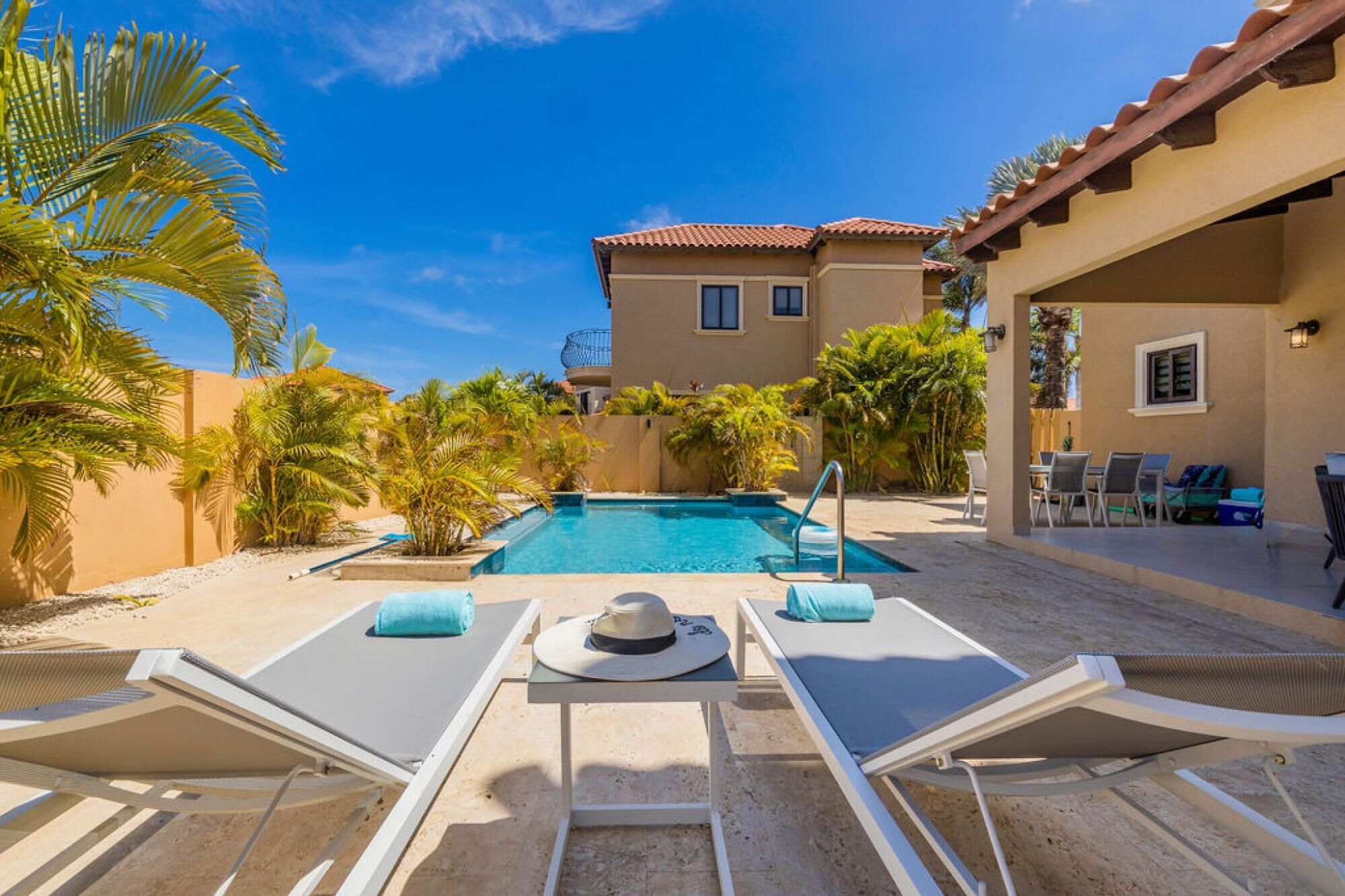 A pool area with lounge chairs, a pool, and a building in the background.
