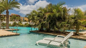 Une piscine à l’eau d’un bleu cristallin, entourée de palmiers et de chaises longues.
