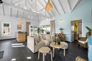Relax in a spacious room with a comfortable seating area, sofa, and wicker chairs, plus a wooden sideboard and decorative tree trunk.