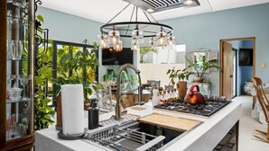 A modern kitchen with a central island, stainless steel appliances, and a variety of plants. - 2BR Private Pool Outdoordining Amazing Gardens (Noord)