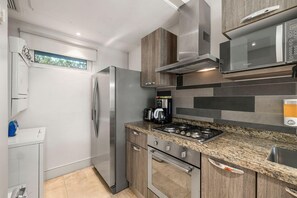 Enjoy cooking in this kitchen with a refrigerator, oven, and microwave, and a window for natural light.