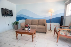 Cozy living space with a sofa, coffee table, armchair, floor lamp, and mounted TV.