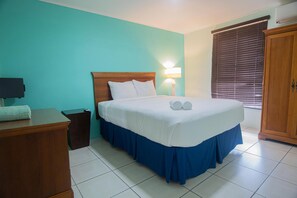 Relax in a spacious room with a large bed, nightstand, and dresser, offering a simple and clean atmosphere.