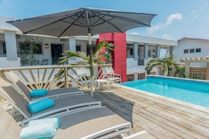 Relax by the pool surrounded by lush greenery and comfortable lounge chairs.
