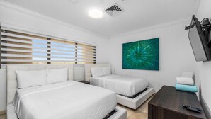 Une chambre d’hôtel avec deux lits, une télévision et une grande fenêtre avec des stores.