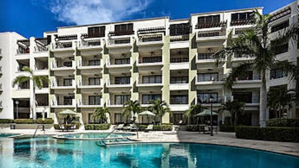 Un hôtel doté de nombreux balcons, d’une piscine et de palmiers.
