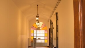 A hallway with a wooden floor, a lantern light fixture, and a door on the right.