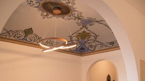 A living room with a sofa, a television, and a decorative ceiling.